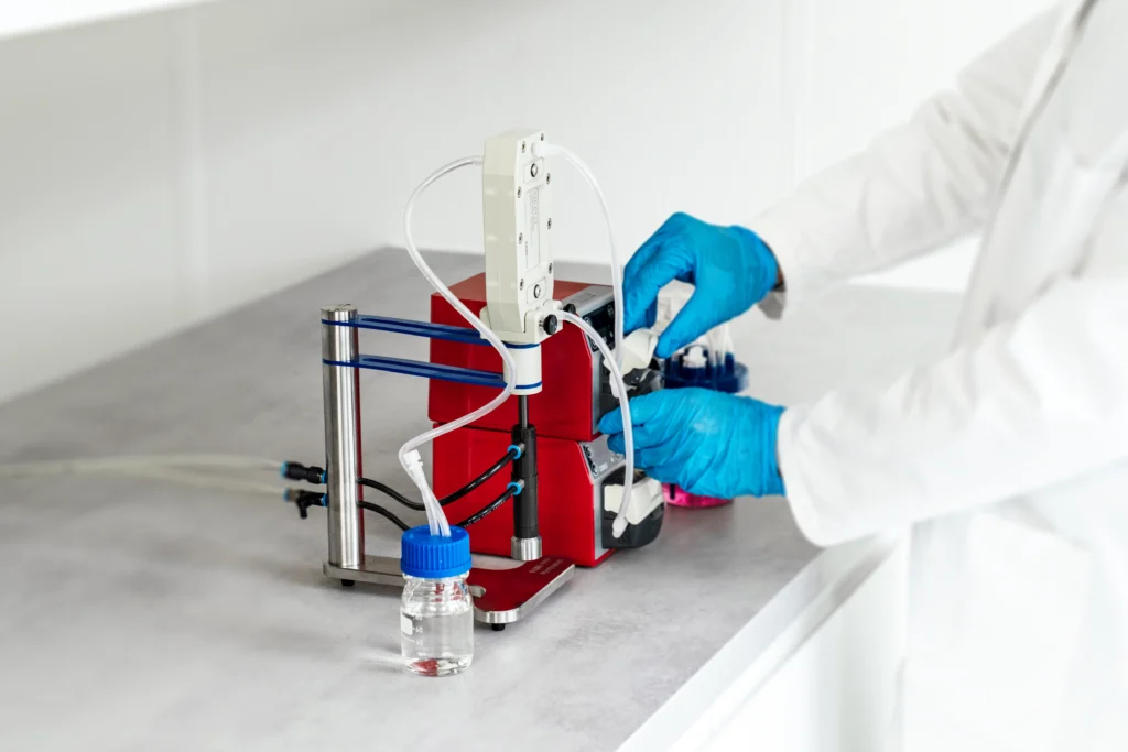 A person wearing a lab coat and gloves operating a Vibro-Lab35 set up with watson marlow pumps